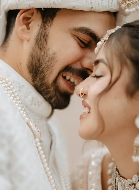 A bride and groom smiling, foreheads close