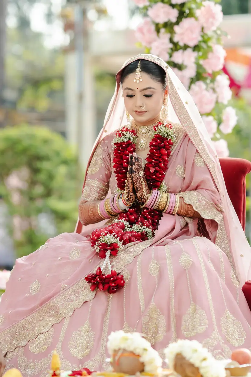 A bride with her varmala beneath a flower mandap
