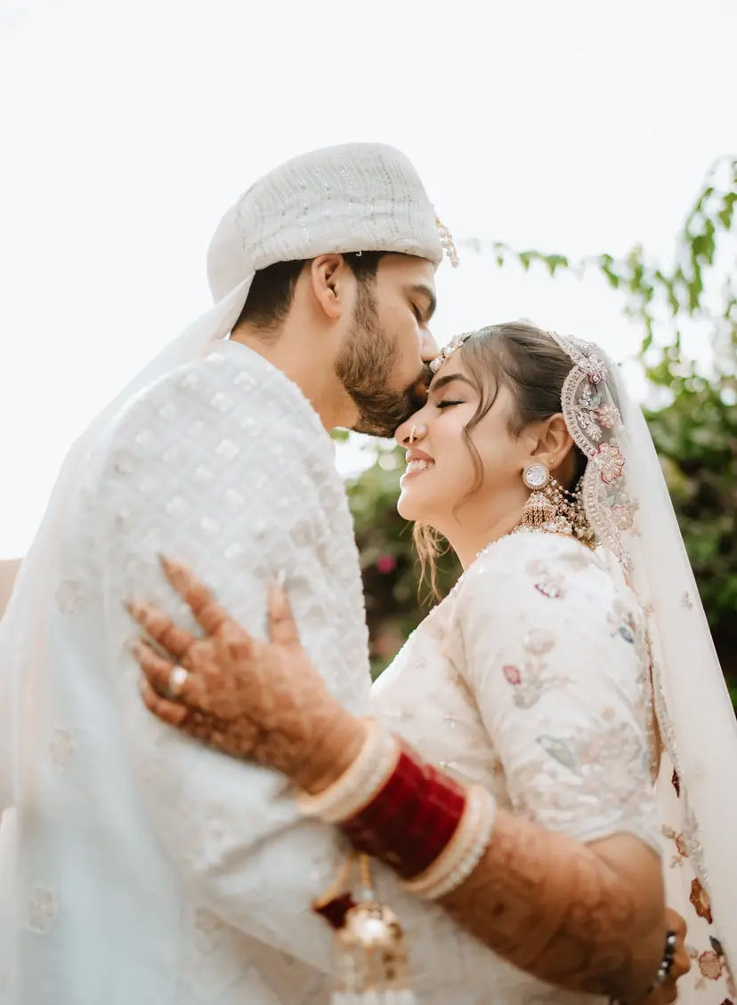 A groom kissing his bride on the forehead